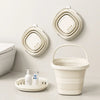 A white foldable plastic bucket with an arc handle is displayed next to several round, white plastic mats on a light surface.