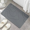 A gray, wavy-patterned bathroom mat is shown next to white flip-flops and a white soap dish.