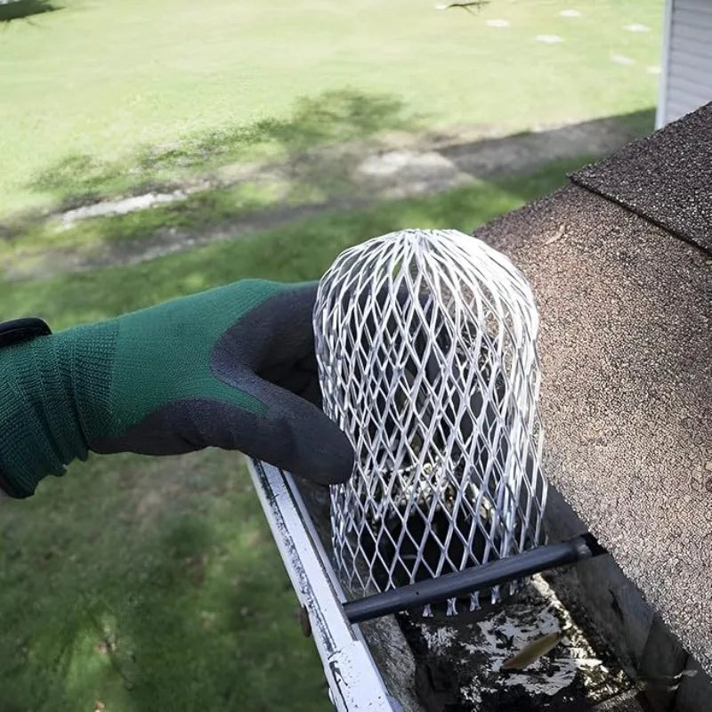Eine Hand mit grüner Handschuh installiert einen Metall-Aluminium-Abflussblattfilter in eine Dachrinne.
