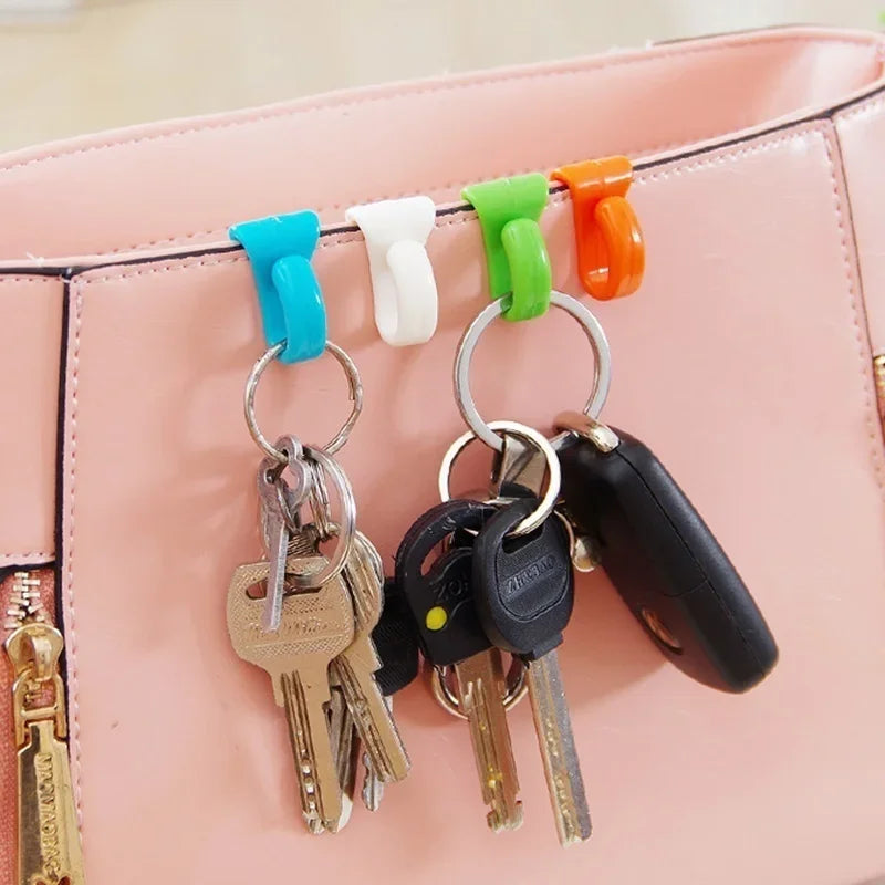 A pink handbag features four colorful key holder clips attached to the strap.