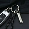 A stainless steel travel pill box and first aid container with a leather cord and keyring.