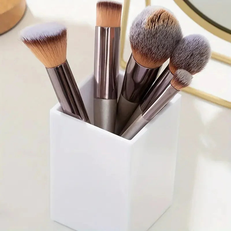 A set of fluffy makeup brushes in various shades are stored upright in a white cosmetic organizer.