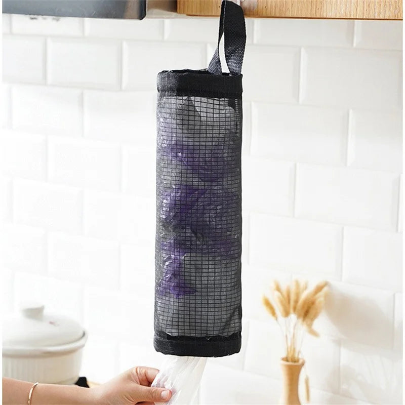 Distributeur de sacs de courses en filet noir suspendu à une étagère, avec une main tenant le fond du sac.