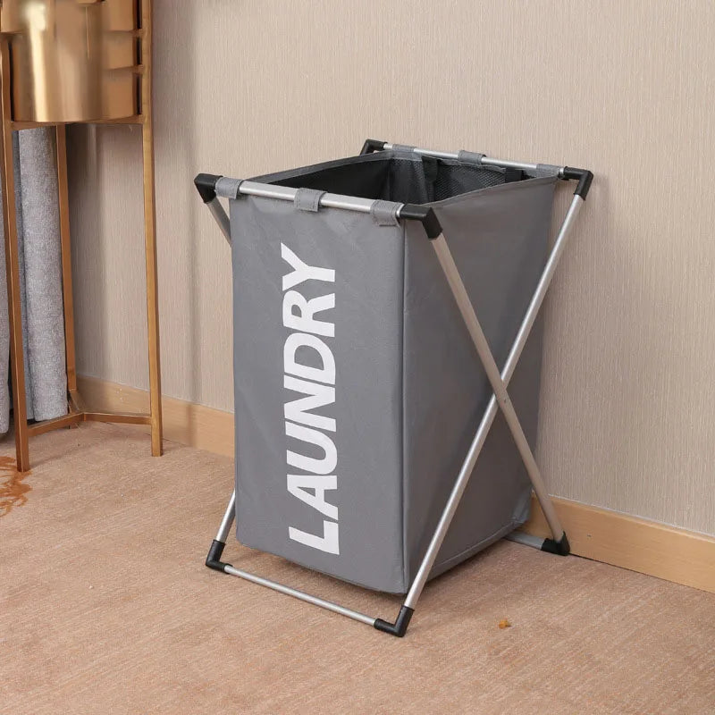 A gray foldable waterproof laundry basket with a metal frame standing on a light carpet.