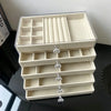 A clear acrylic 5-tier desktop jewelry organizer rack with multiple compartments and decorative glass accents.
