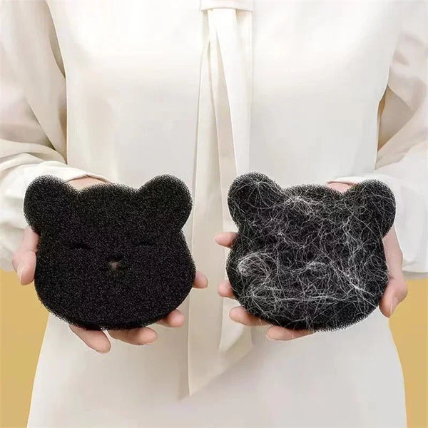 A pair of hands holds two black felt cat-shaped pet hair removers against a white background.