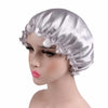 A silver satin sleep bonnet displayed on a mannequin head.