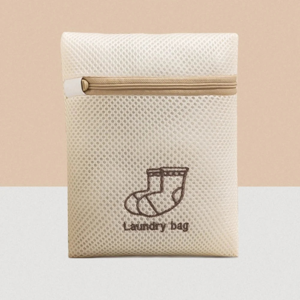 A beige reusable zippered laundry bag with a light tan zipper and a simple outline of a sock design.