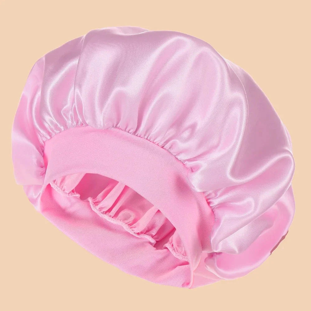 A pink satin wide brim shower cap folded and displayed against a light background.