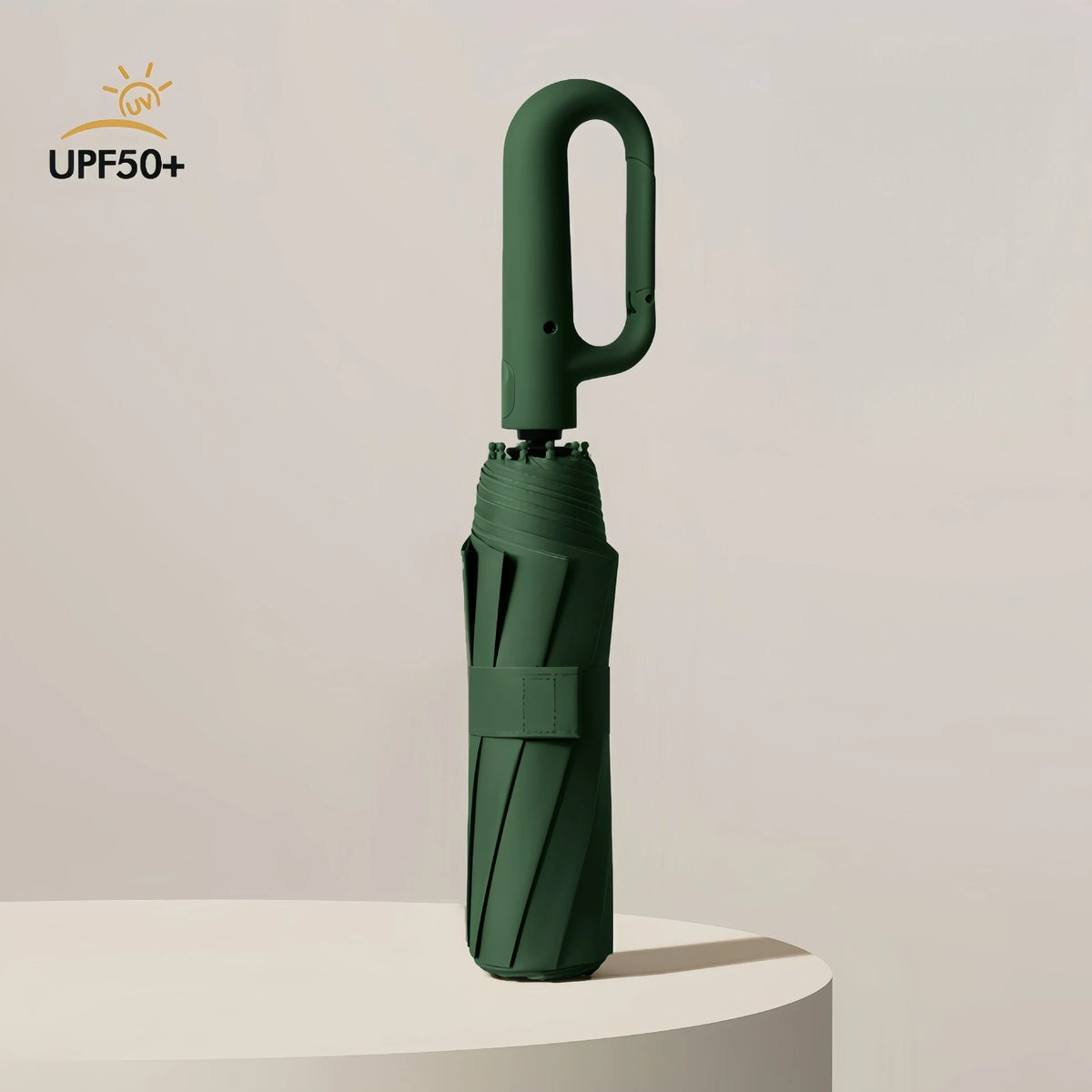 A dark green windproof automatic folding umbrella standing upright on a white surface.