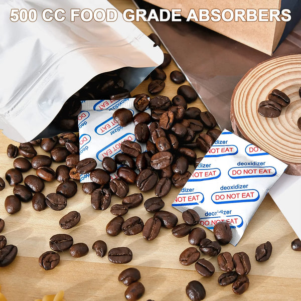 A pile of dark roasted coffee beans next to white food grade oxygen absorbers on a wooden surface.