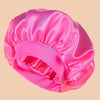 A bright pink satin wide brim shower cap folded and displayed against a neutral background.