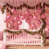 Guardería o dormitorio temático rosa decorado con guirnaldas florales y globos de aluminio colgados.