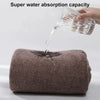A hand pours water onto a brown bath wrap towel demonstrating its super water absorption capacity.