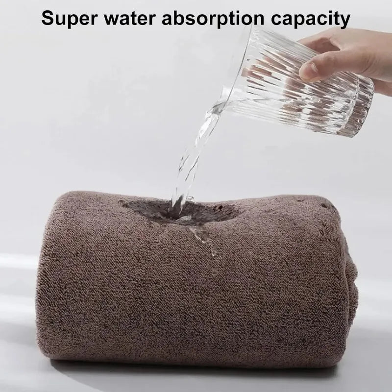 A hand pours water onto a brown bath wrap towel demonstrating its super water absorption capacity.