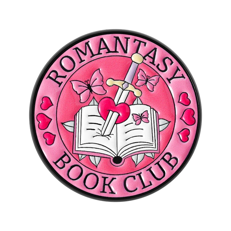 Insignia de esmalte rosa con mariposa y espada de plata sobre un libro abierto con corazón rosa.