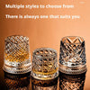 Un juego de dos elegantes vasos de whisky giratorios con patrones de vidrio tallado, mostrados sobre una superficie reflectan