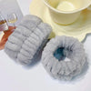 A set of gray microfiber wrist sweatbands for face washing and skincare placed next to a yellow bowl.