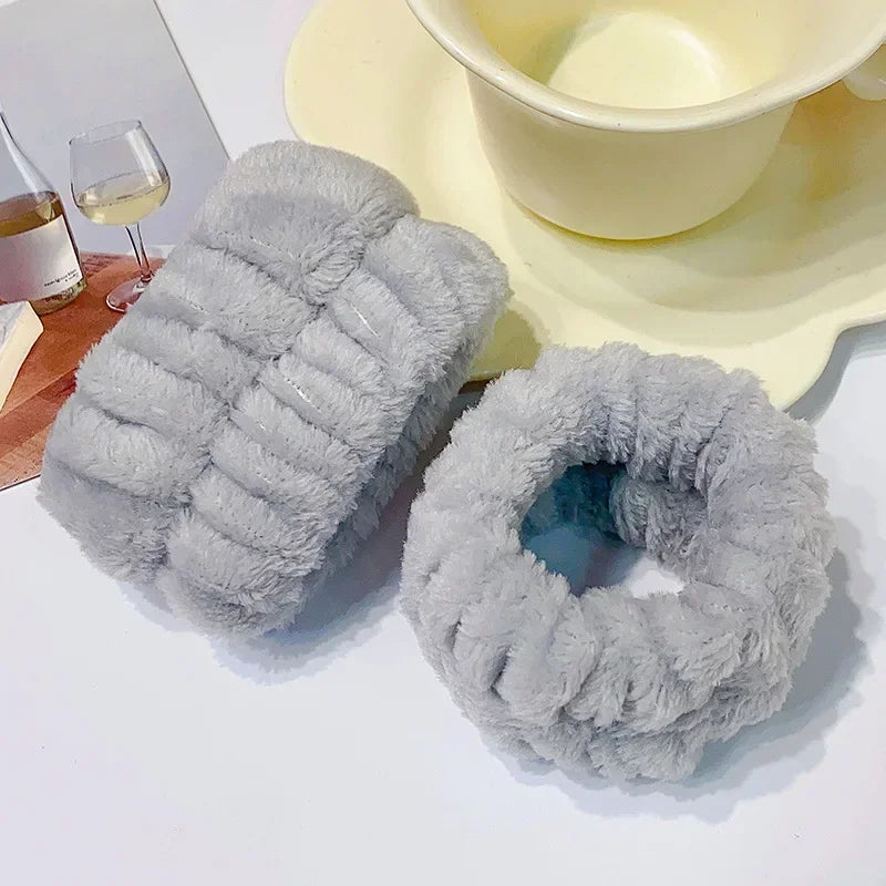 A set of gray microfiber wrist sweatbands for face washing and skincare placed next to a yellow bowl.