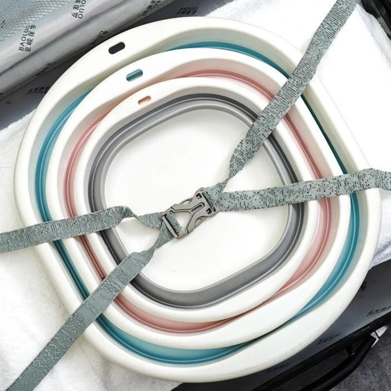 A stack of foldable plastic wash basins in various shades of white, gray, and pink resting on a white cloth.