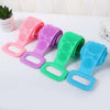 A collection of colorful long-handle silicone body scrubbers with detachable loofahs arranged on a white surface.