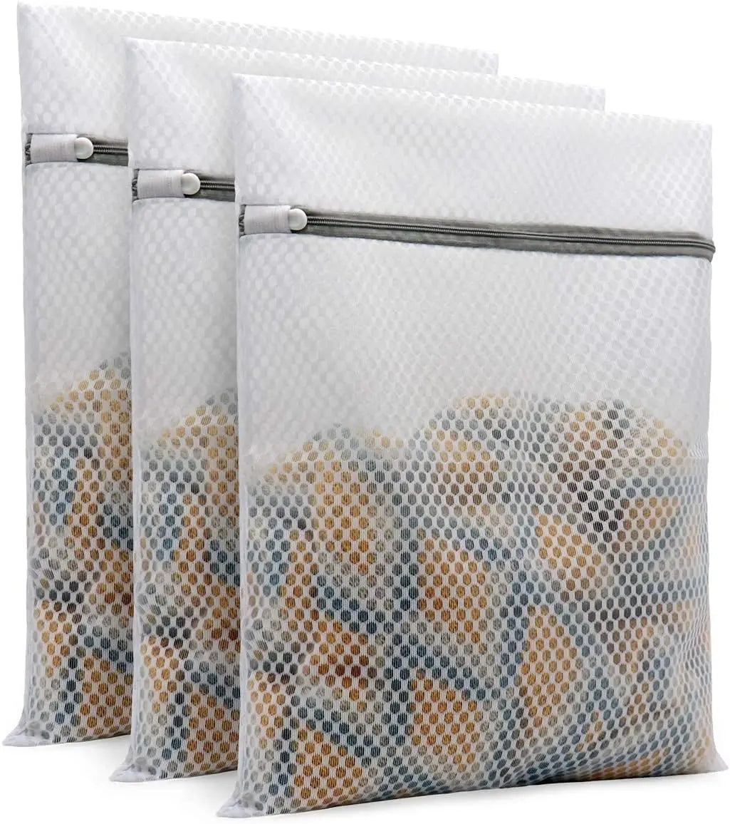 Ein Set aus weißen Wabennetz-Waschtaschen mit grauen Reißverschlüssen, gefüllt mit verschiedenfarbiger Wäsche.