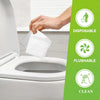 A hand is placing a clear disposable toilet seat cover into the bowl of a white toilet.
