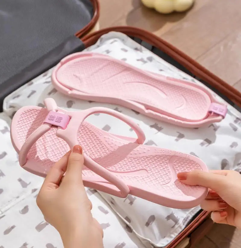 Une personne tient une sandale EVA pliante rose sur un tissu blanc, montrant la texture de la semelle.