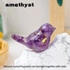 A purple amethyst crystal bird statue resting on a white rock surface.