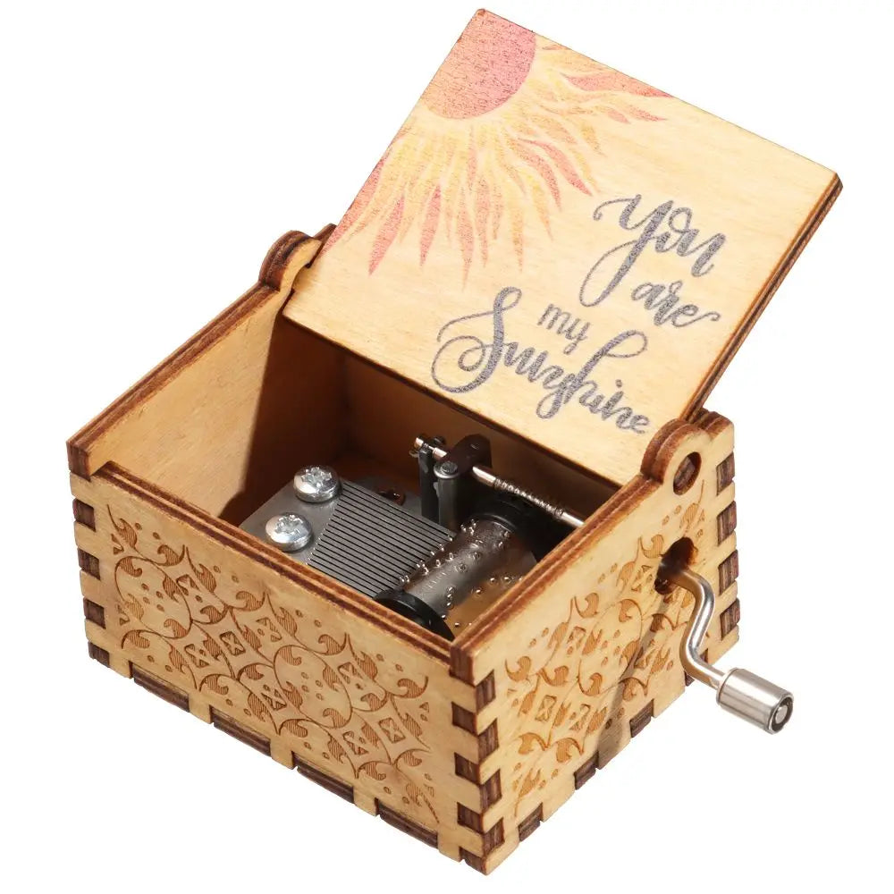 Caja de música de madera manual con tapa que presenta un diseño de sol y un pequeño mecanismo metálico.