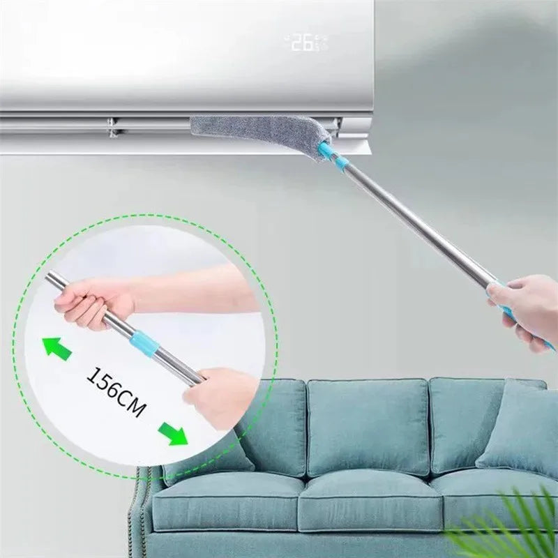 A hand is using an extendable telescopic mop with a green handle to clean a surface near a refrigerator.