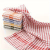 A stack of absorbent cotton cleaning cloths in various plaid patterns, including red and white.