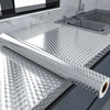Roll of self-adhesive aluminum foil kitchen wall sticker used as a backsplash protector on a stainless steel sink area.