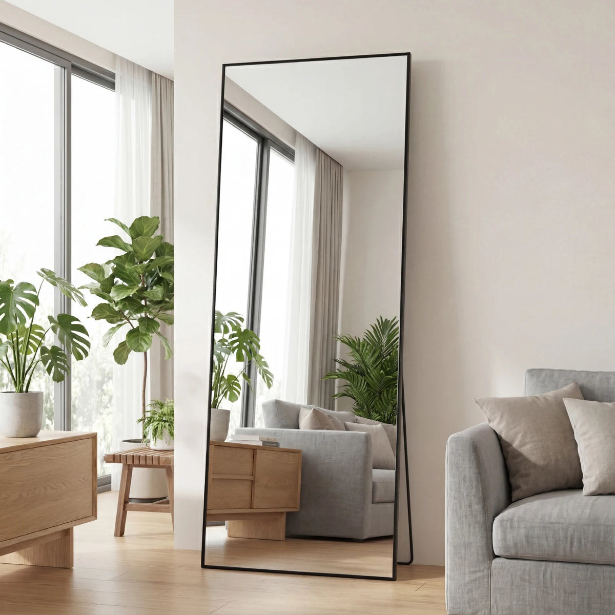 Ein vollflächiger Spiegel mit schwarzem Aluminiumrahmen, der ein helles Interieur und Grün reflektiert.