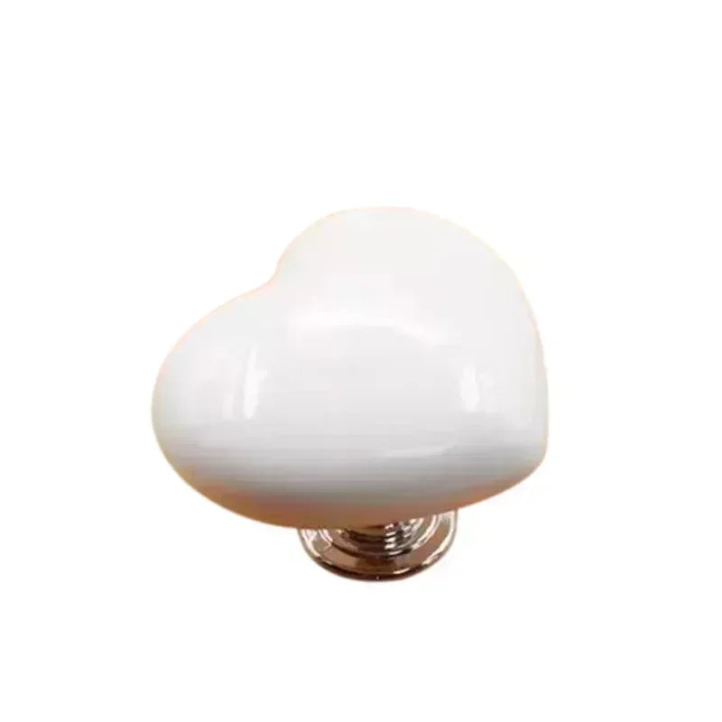 A white heart-shaped toilet presser button with a silver base.