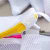 Close-up of white reusable mesh laundry bags with yellow zippers and pink accents.