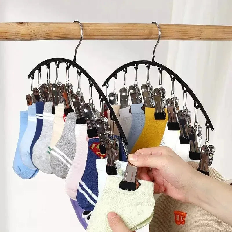 Gebogene Haken mit Mehrzweckclips hängen von einem Holzstab, zeigen verschiedene bunte Kleidung und Accessoires.