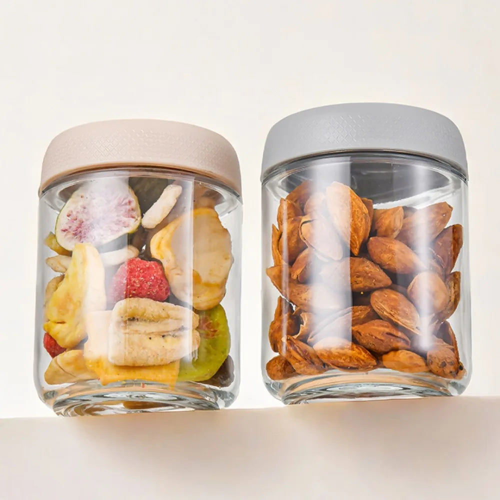 Two glass meal prep jars with airtight lids filled with sliced fruit and nuts.
