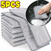 Five pieces of gray thickened metal wire cleaning cloths being used to clean a black pot.