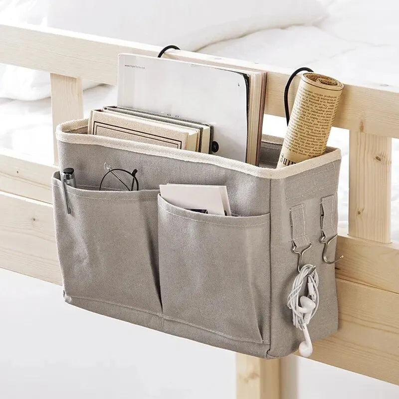A gray fabric storage pouch with multiple compartments is displayed on a wooden bedside rack.