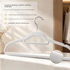 White non-slip velvet hangers with chrome hooks displayed on a wooden surface.