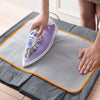 A hand is using a purple heat resistant ironing cloth and press guard on a gray ironing board.