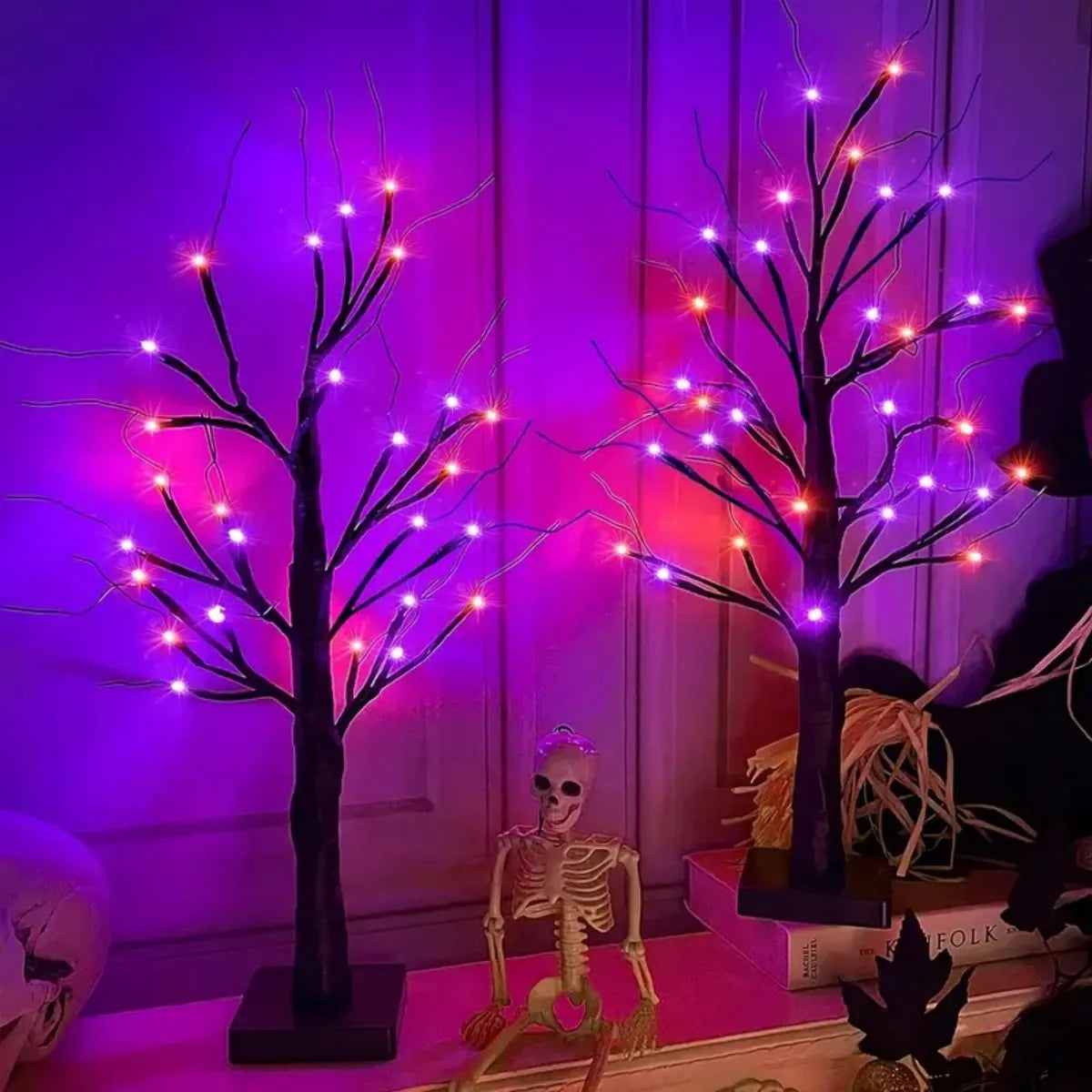 Dekorativer Birkenbaumleuchte mit orange- und lila LED-Lichtern vor dunklem Hintergrund.
