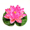 A vibrant pink artificial lotus flower blooming on green leaves.