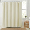 A cream-colored waffle weave shower curtain hanging from a metal rod in a bathroom setting.