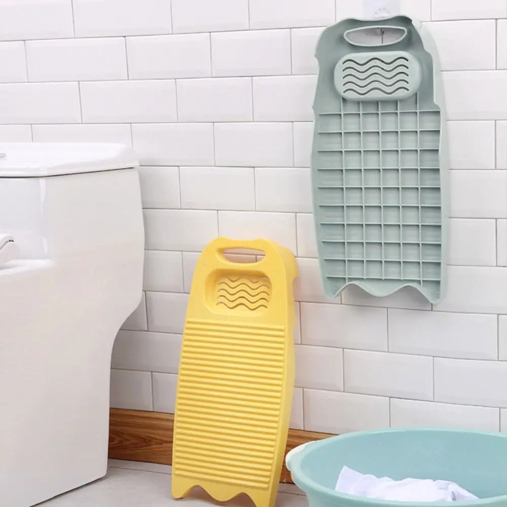 A light green plastic washing board with a soap holder is mounted on a white tiled wall next to a toilet.