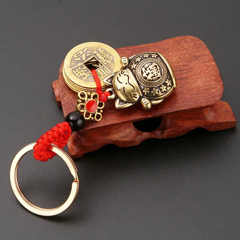 Vintage gold-tone lucky cat keychain with a red tassel attached to a wooden block