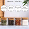 Four glass spice jars with bamboo lids showing various dried herbs and spices on a white marble surface