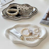 A silver tray holds various pieces of white pearl and silver jewelry, including necklaces and rings.