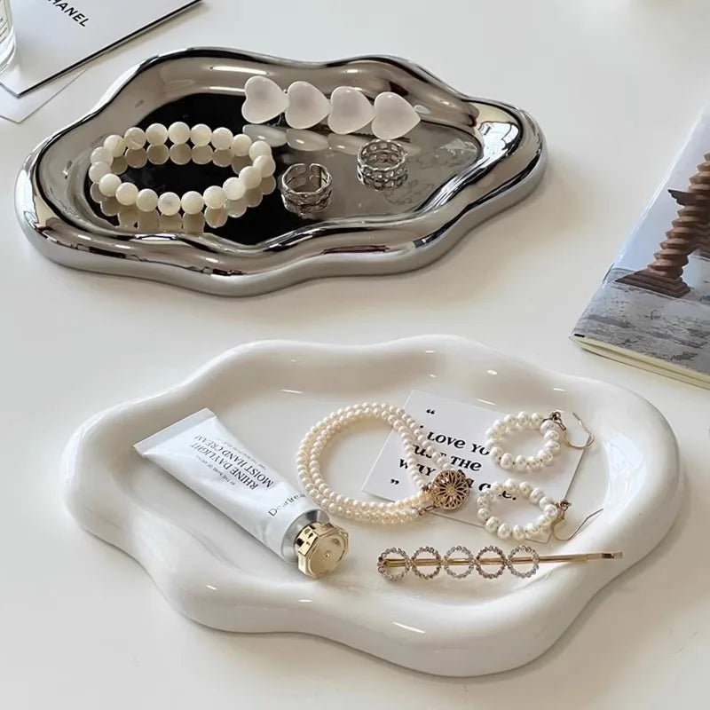 A silver tray holds various pieces of white pearl and silver jewelry, including necklaces and rings.